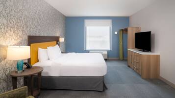 Une chambre d’hôtel avec un lit, une télévision, un bureau avec une lampe et une fenêtre.