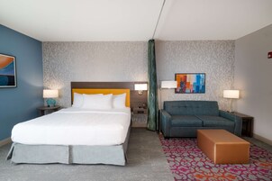 Habitación de hotel con cama, sofá, una mesita y alfombra estampada.
