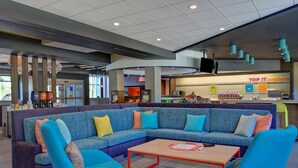 A modern lounge area with a sectional sofa, armchairs, and a coffee table. - Tru by Hilton Rocky Mount (Rocky Mount)