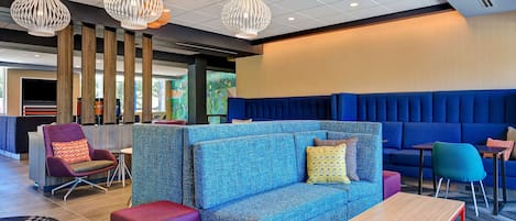 A modern lounge area with a blue sofa, purple armchair, and a wooden table.