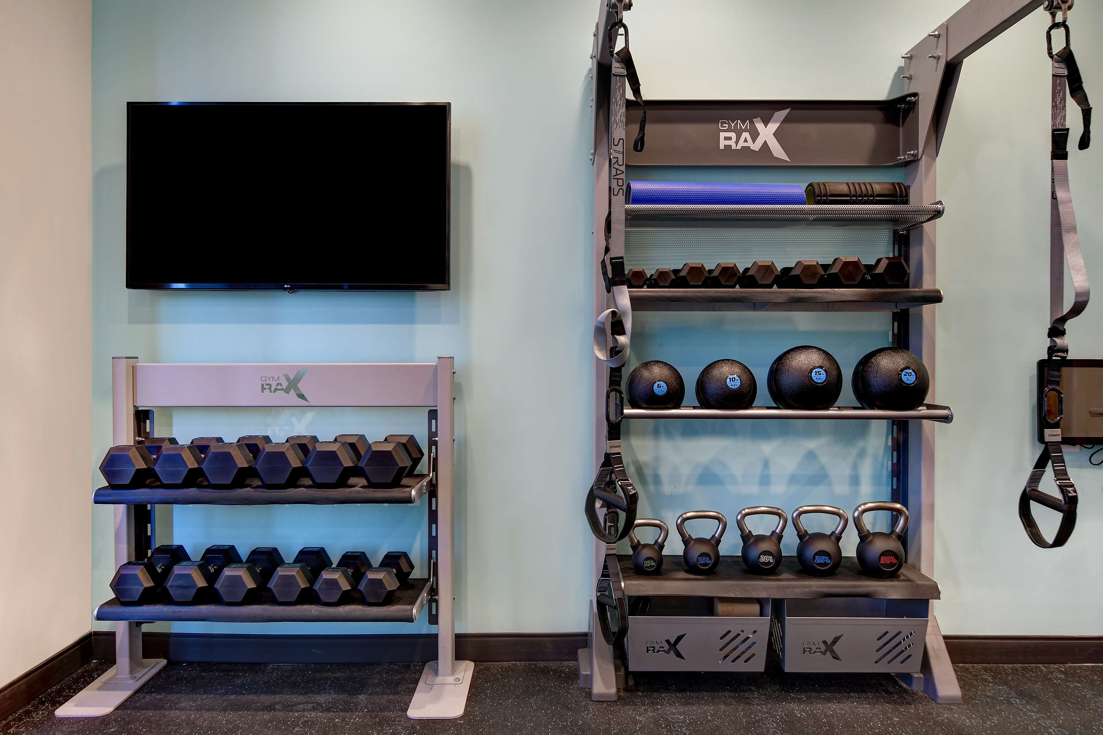 Uma academia com equipamentos como halteres, kettlebells e bolas de medicina.