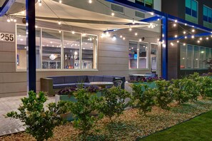 Een modern gebouw met een bord waarop '255' staat, een terras en sfeerverlichting.