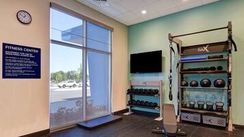 A fitness center with a large window, a treadmill, weight racks, and a television.