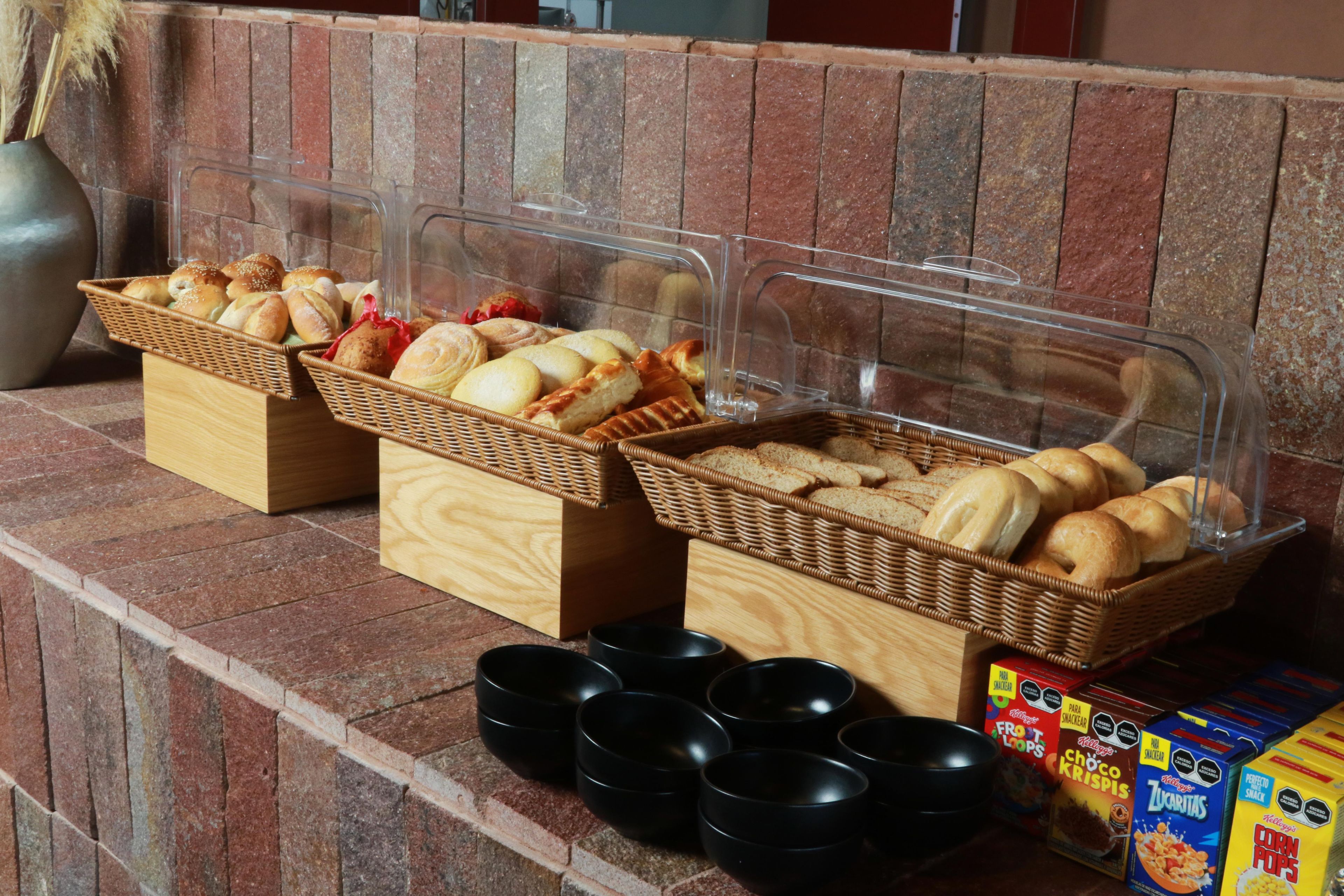 A buffet setup with various baked goods and cereal boxes.