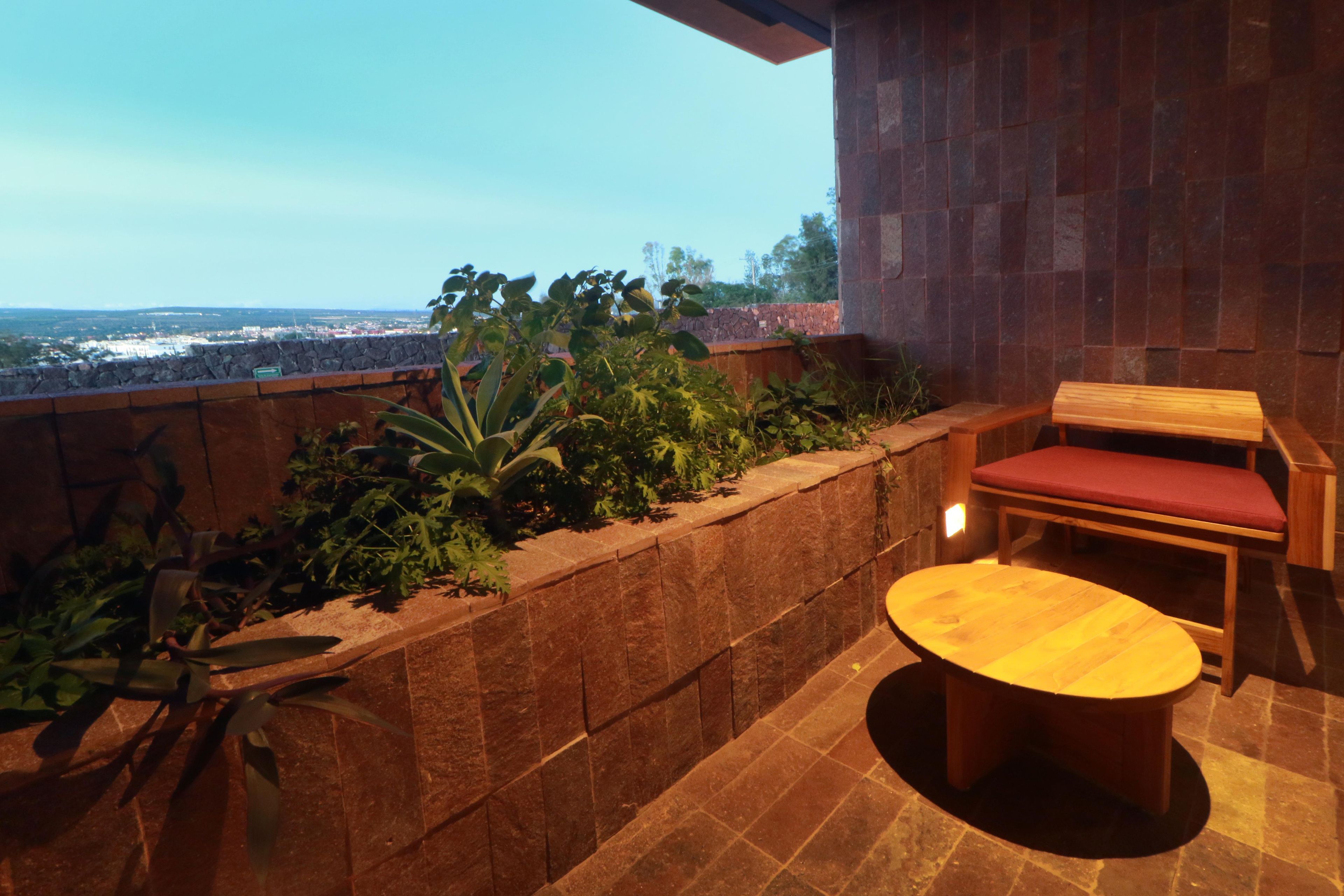 Una terrazza con un muro in pietra, una panchina di legno e un tavolo rotondo.