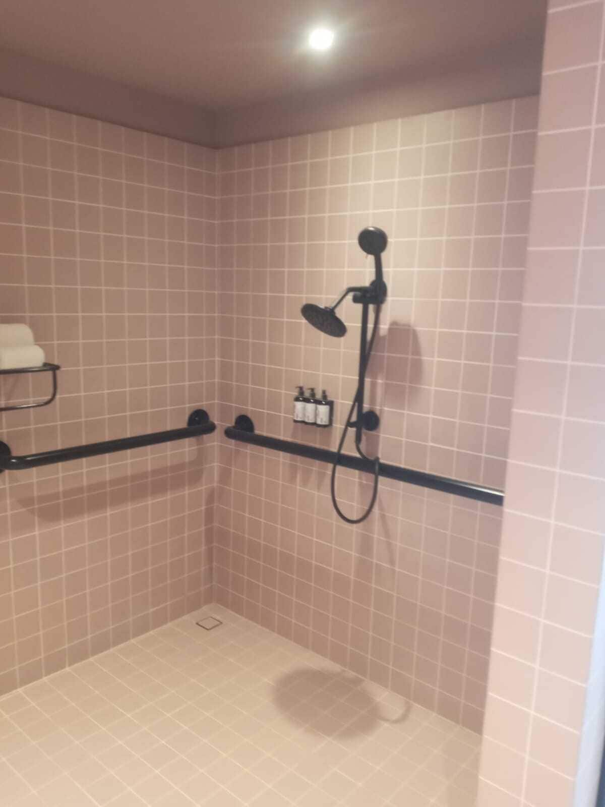 Un área de ducha pequeña con azulejos, un cabezal de ducha manual y un accesorio de ducha de mano.