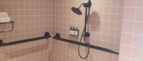 Un área de ducha pequeña con azulejos, un cabezal de ducha manual y un accesorio de ducha de mano.