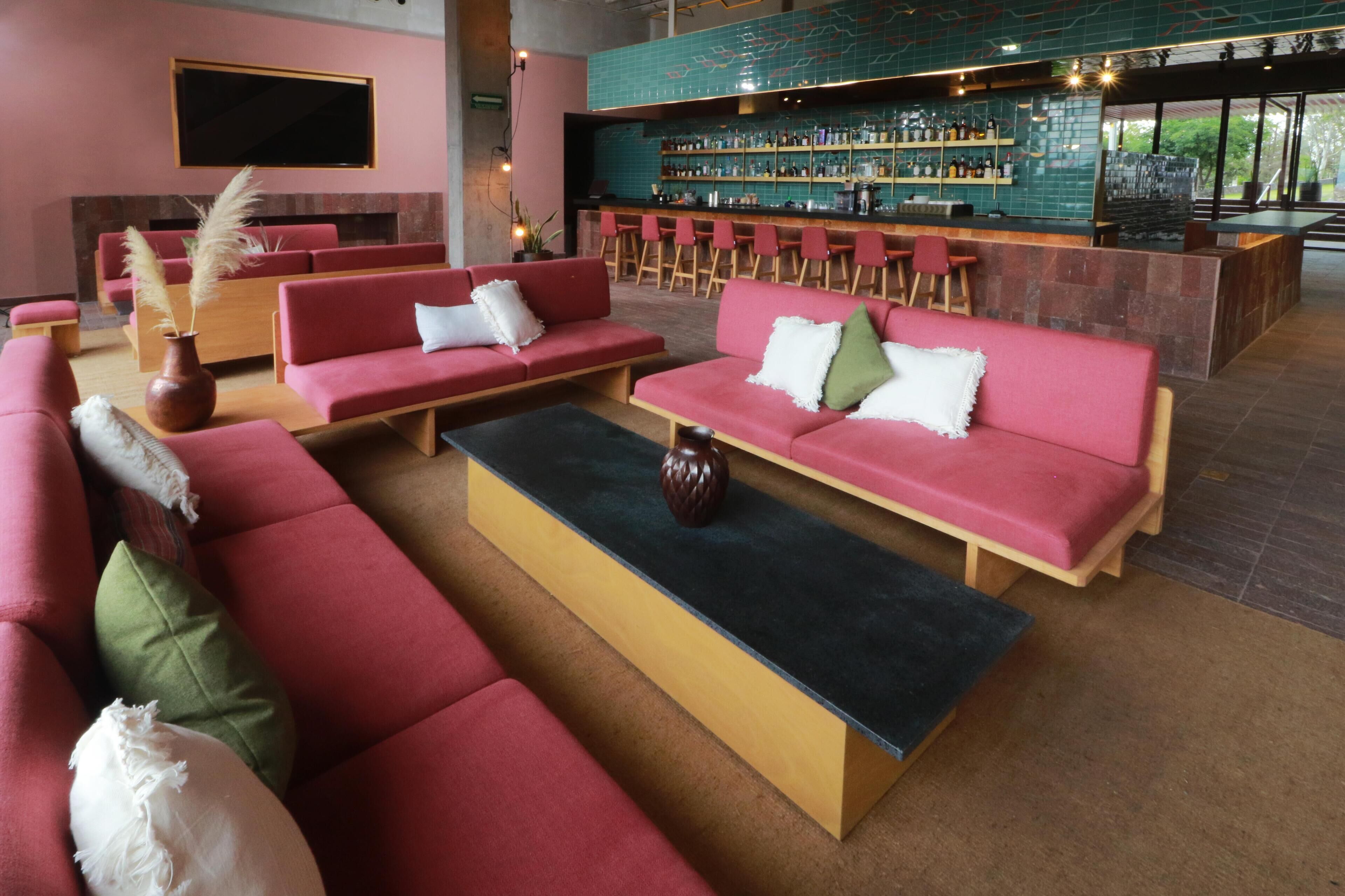 Zona de bar moderna con asientos rojos y una barra.