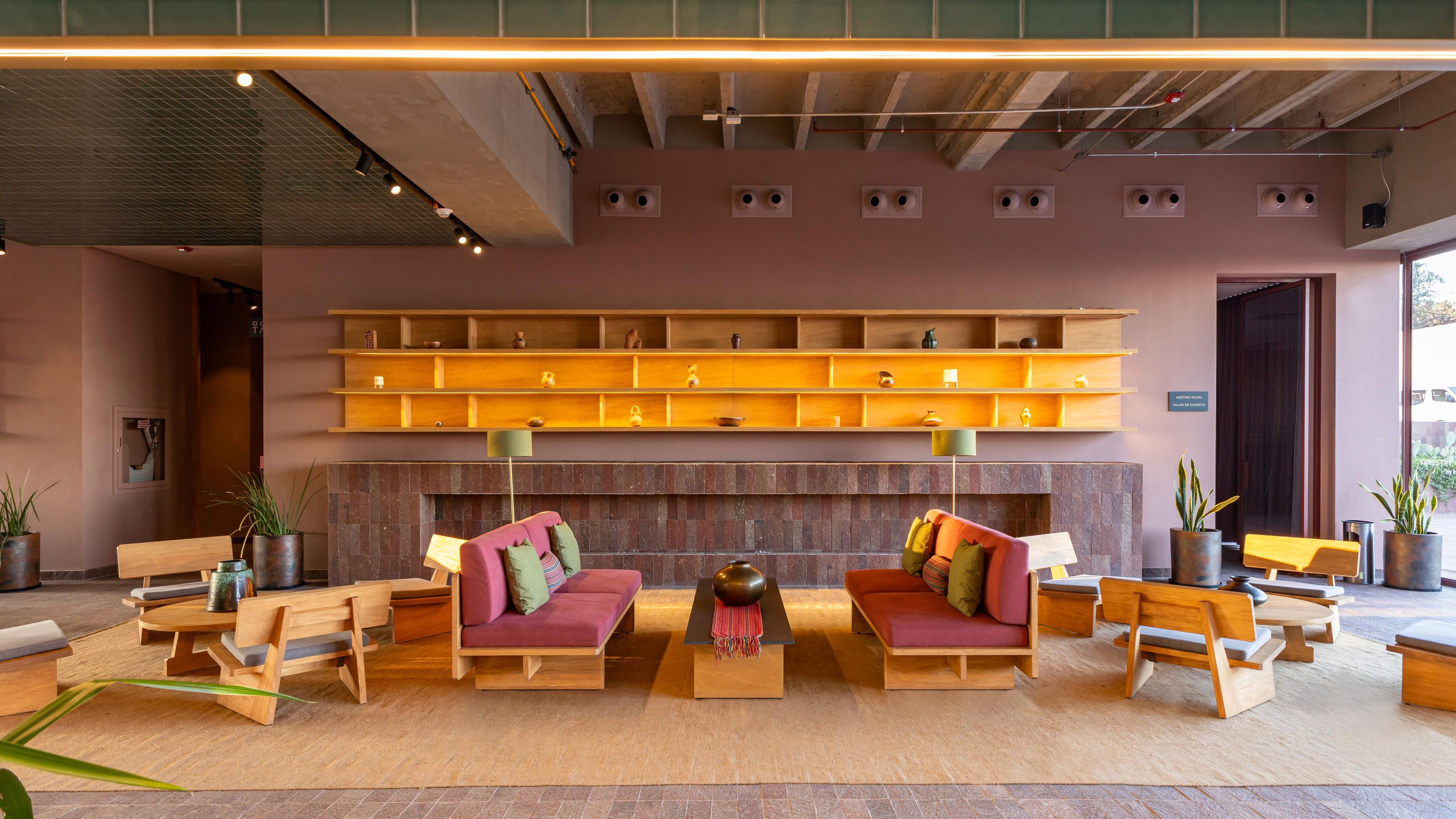 A modern lobby with wooden furniture, a fireplace, and a wall-mounted shelf with decorative items.