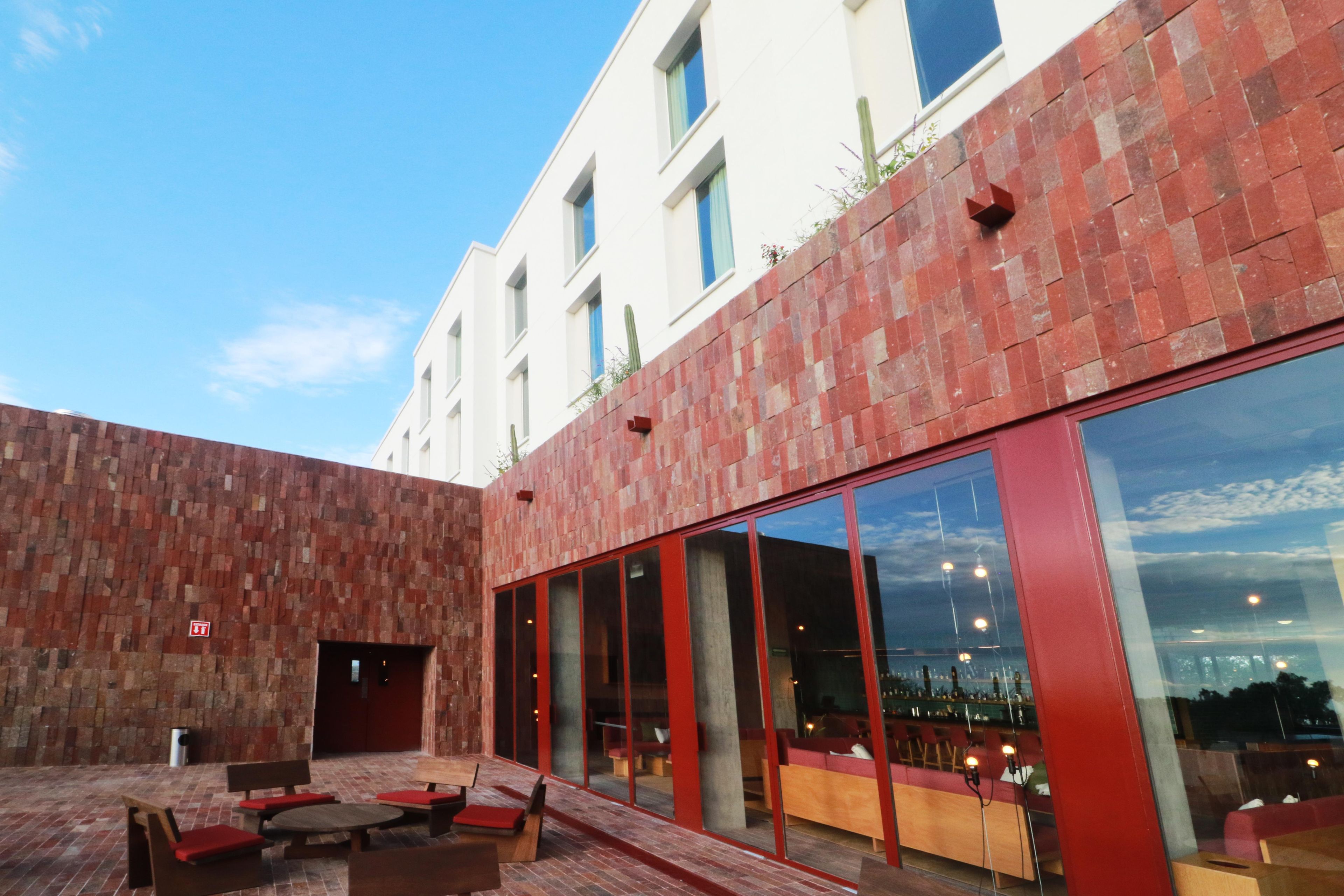 An outdoor seating area with red brick walls and large windows.