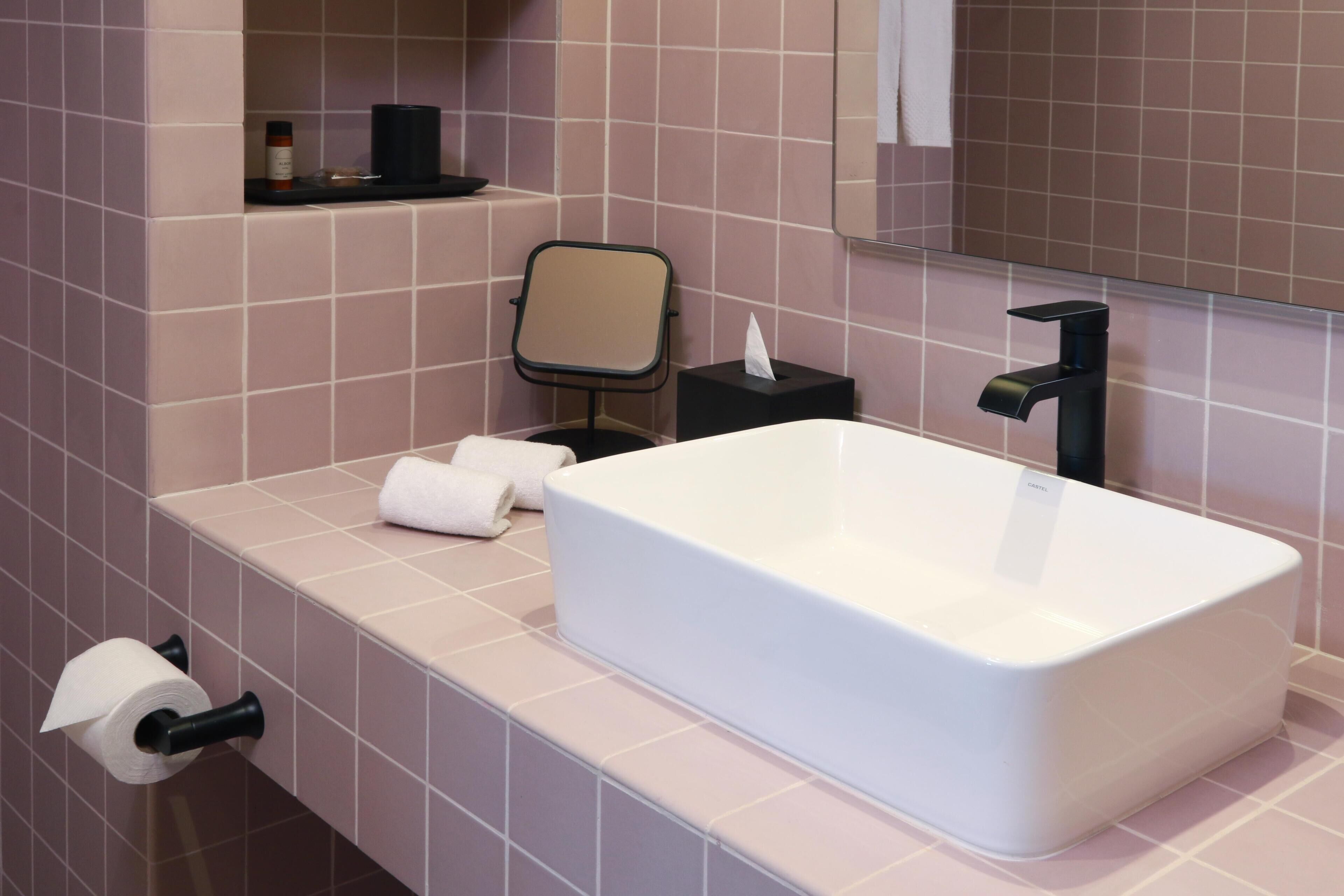 A modern bathroom with a white bathtub, a black toilet, and a mirror above the sink.