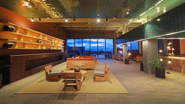 A spacious lobby with a modern design, featuring a seating area with sofas and a table, a large window offering a view of the cityscape, and a decorative wall with shelves. - Albor San Miguel de Allende, Tapestry Collection by Hilton (San Miguel de Allende)