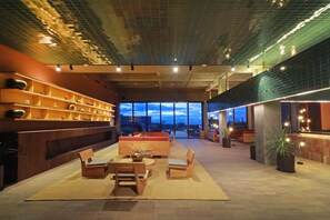 A spacious lobby with a modern design, featuring a seating area with sofas and a table, a large window offering a view of the cityscape, and a decorative wall with shelves. - Albor San Miguel de Allende, Tapestry Collection by Hilton (San Miguel de Allende)