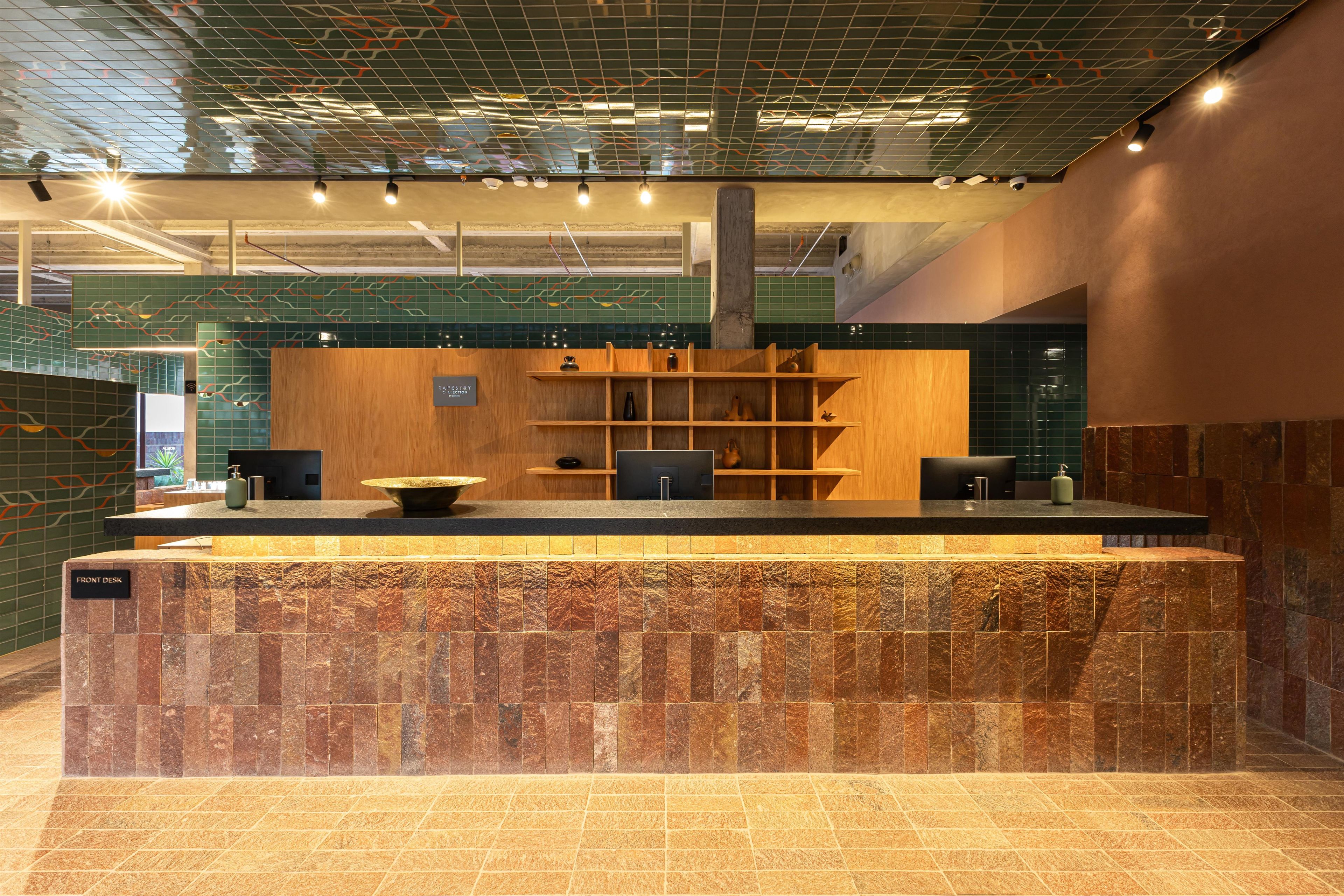 A reception area with a marble counter, wooden shelves, and a tiled wall.