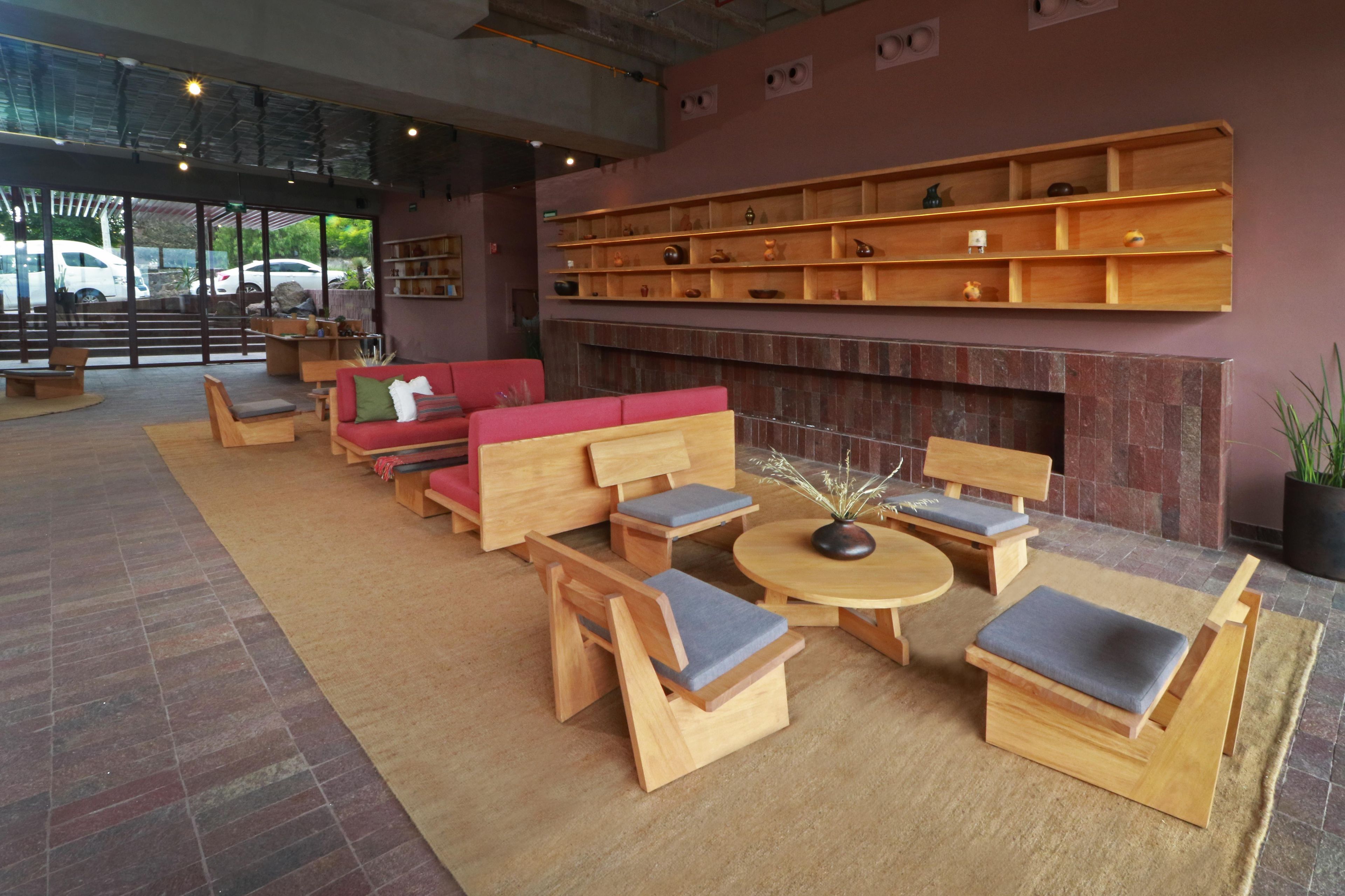 A modern interior with a red sofa, wooden chairs, a round table, and a fireplace.