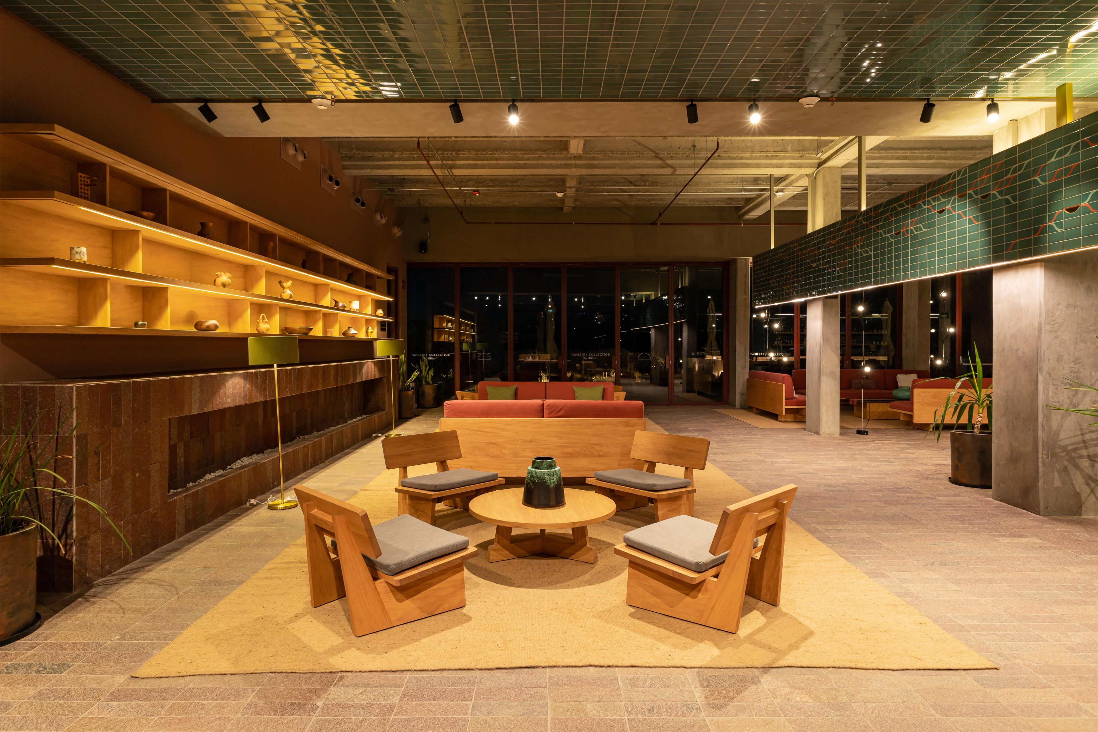 A spacious lobby with a central seating area, a wall-mounted shelf with decorative items, and a patterned ceiling.