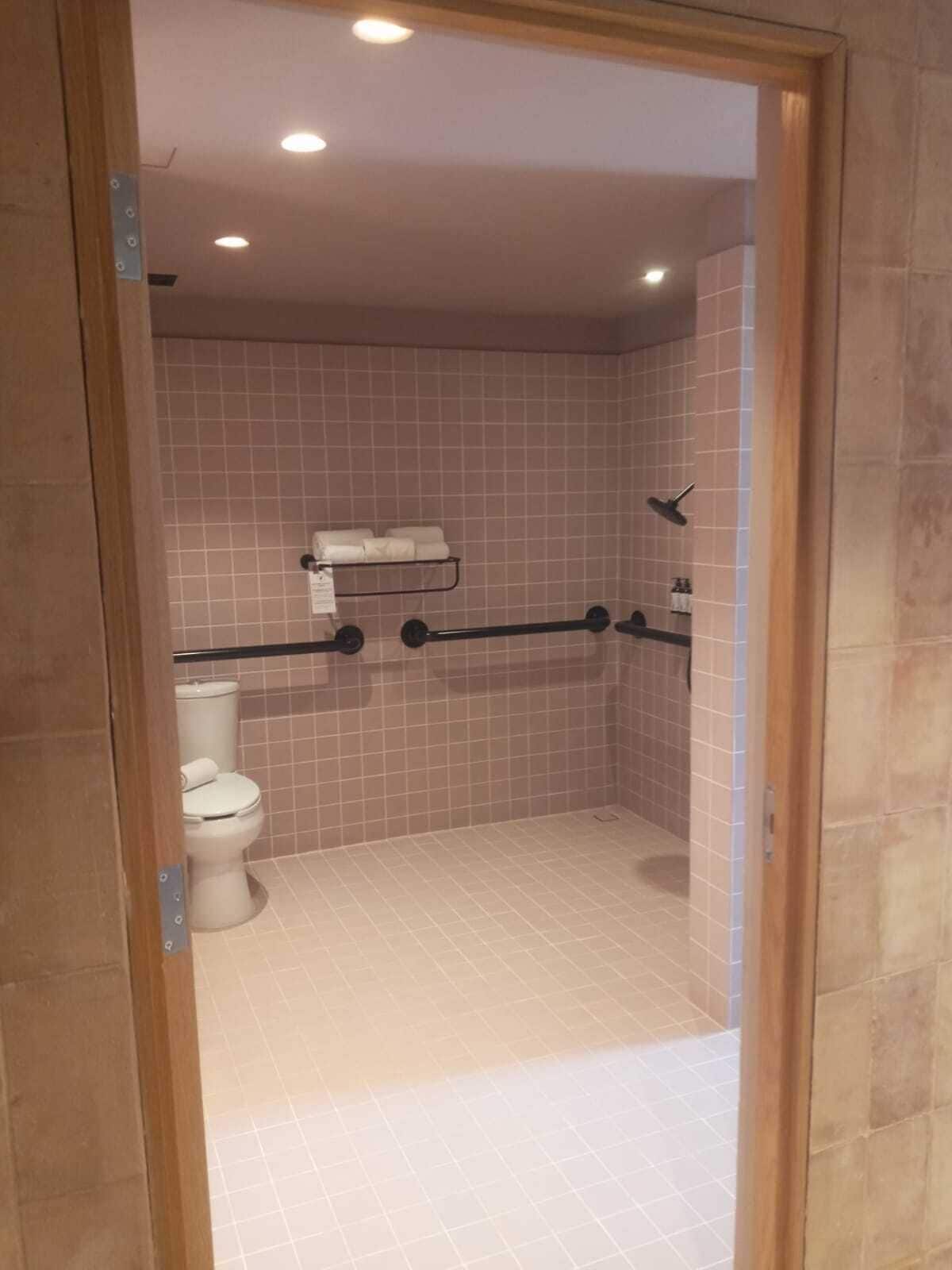 Un baño pequeño con azulejos, que incluye un inodoro, zona de ducha y un perchero para toallas.