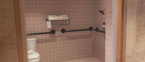 Un baño pequeño con azulejos, que incluye un inodoro, zona de ducha y un perchero para toallas.