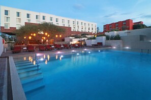A swimming pool with steps leading into it, surrounded by lounge chairs and a building in the background. - Albor San Miguel de Allende, Tapestry Collection by Hilton (San Miguel de Allende)