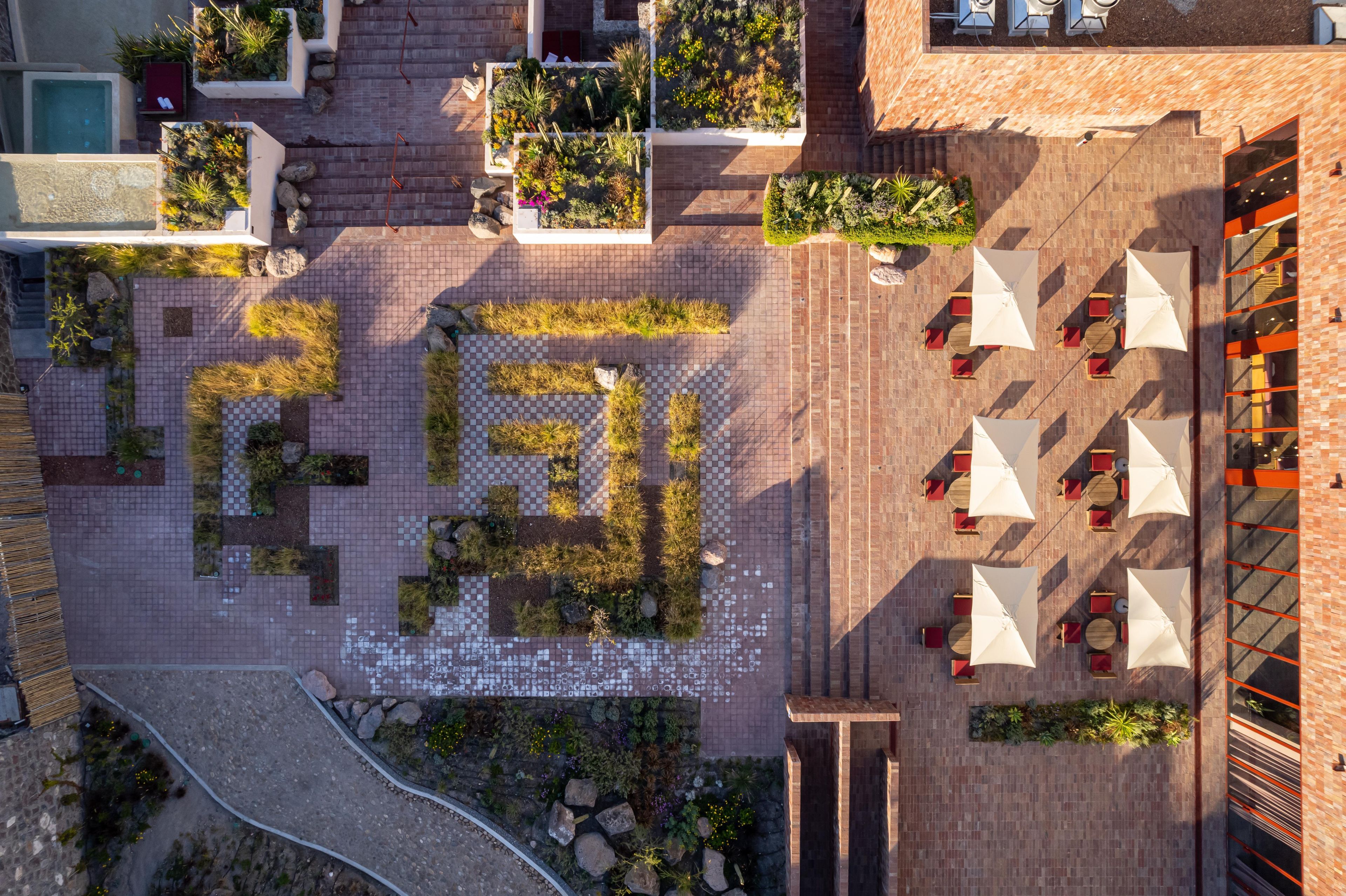 An aerial view of a courtyard with a checkered pattern, outdoor seating, and planters.