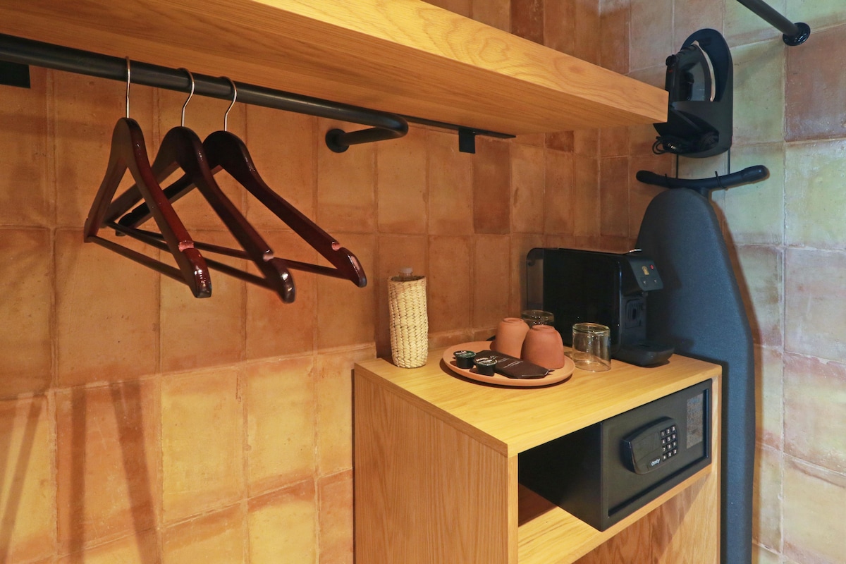 Een houten plank met een koffieapparaat, een bord met toevoegingen en een gevlochten mand.
