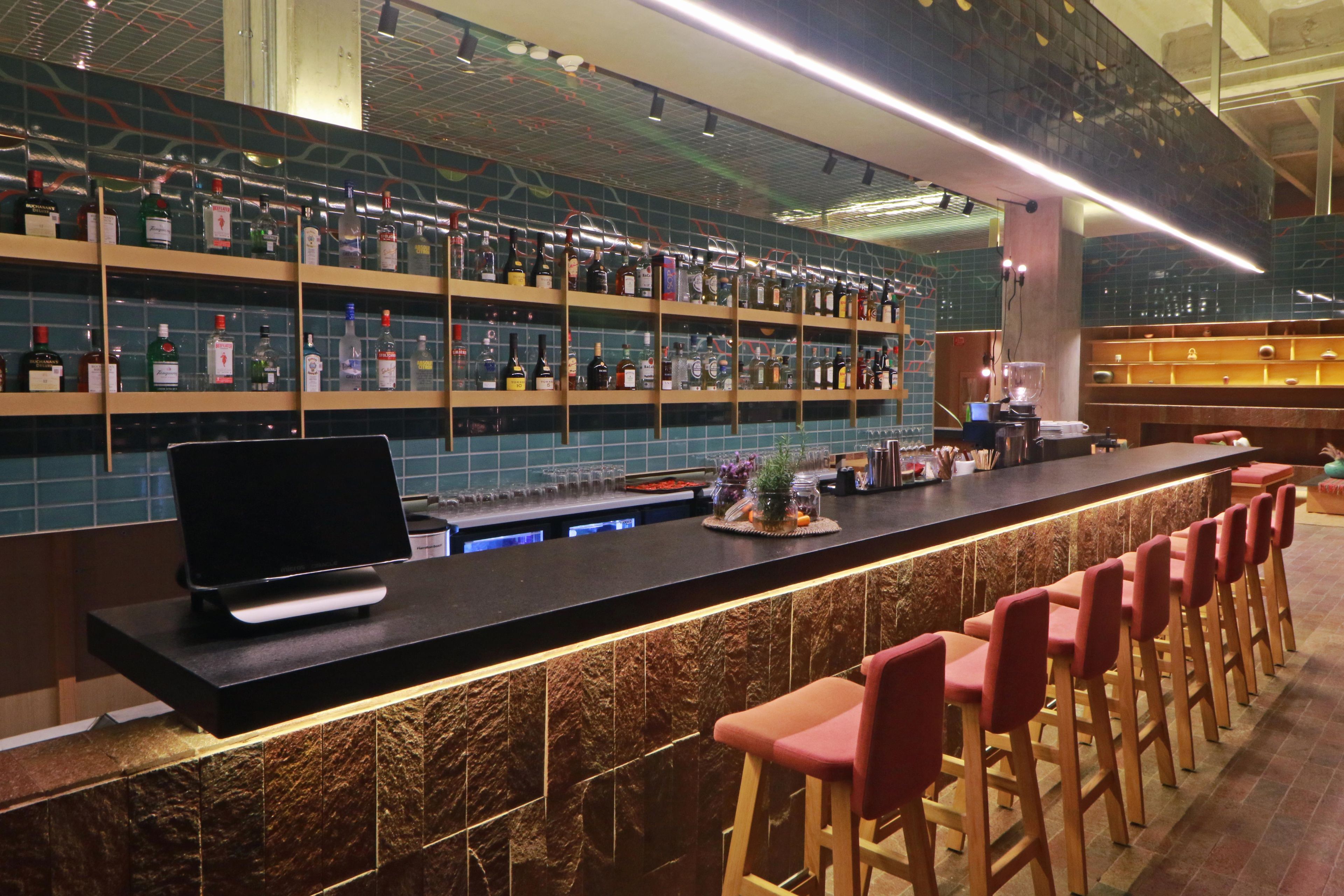 A bar area with shelves of bottles, a flat-screen TV, and bar stools.