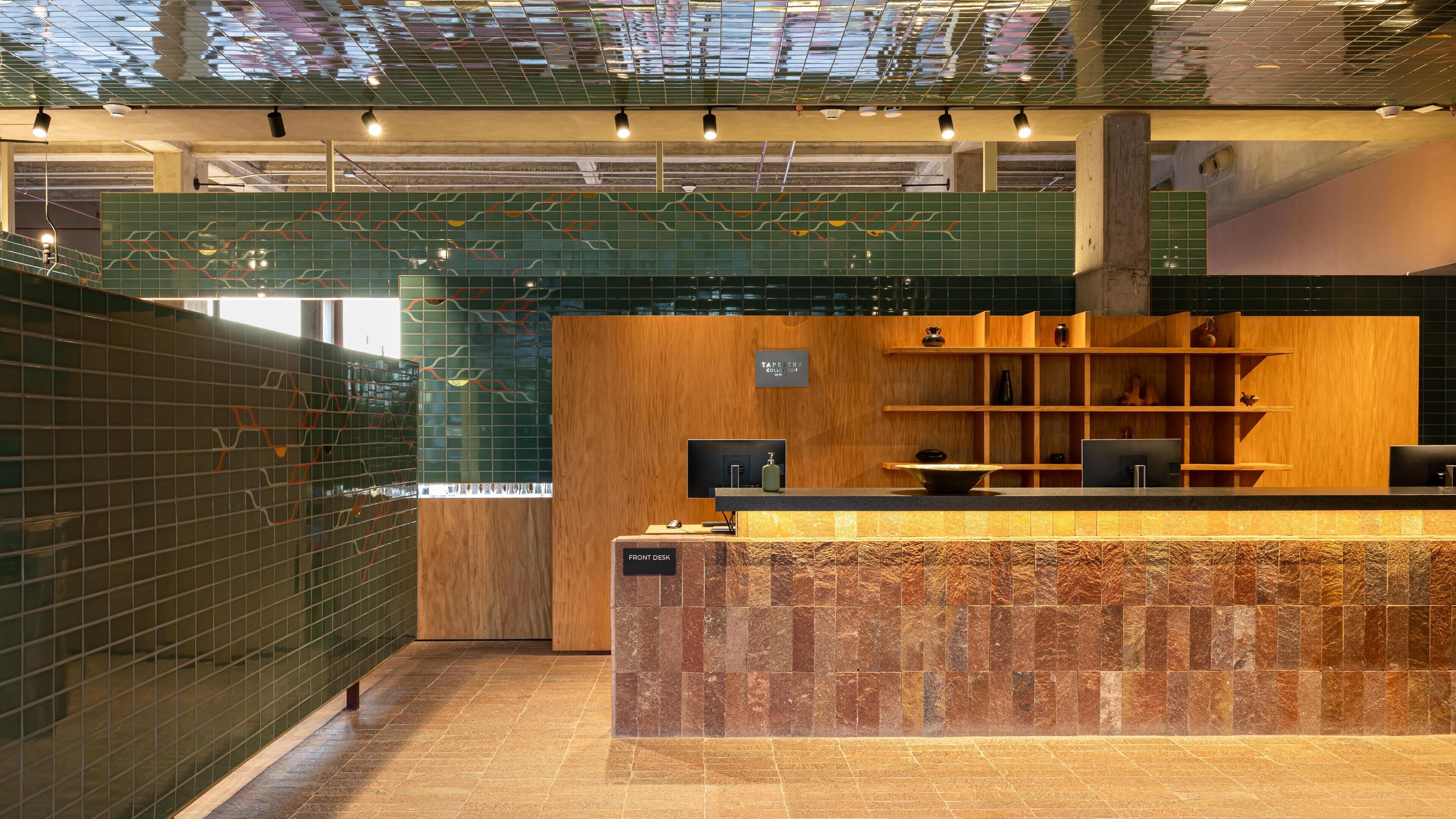 A modern reception area with a wooden desk, a computer, and a shelf with decorative items.