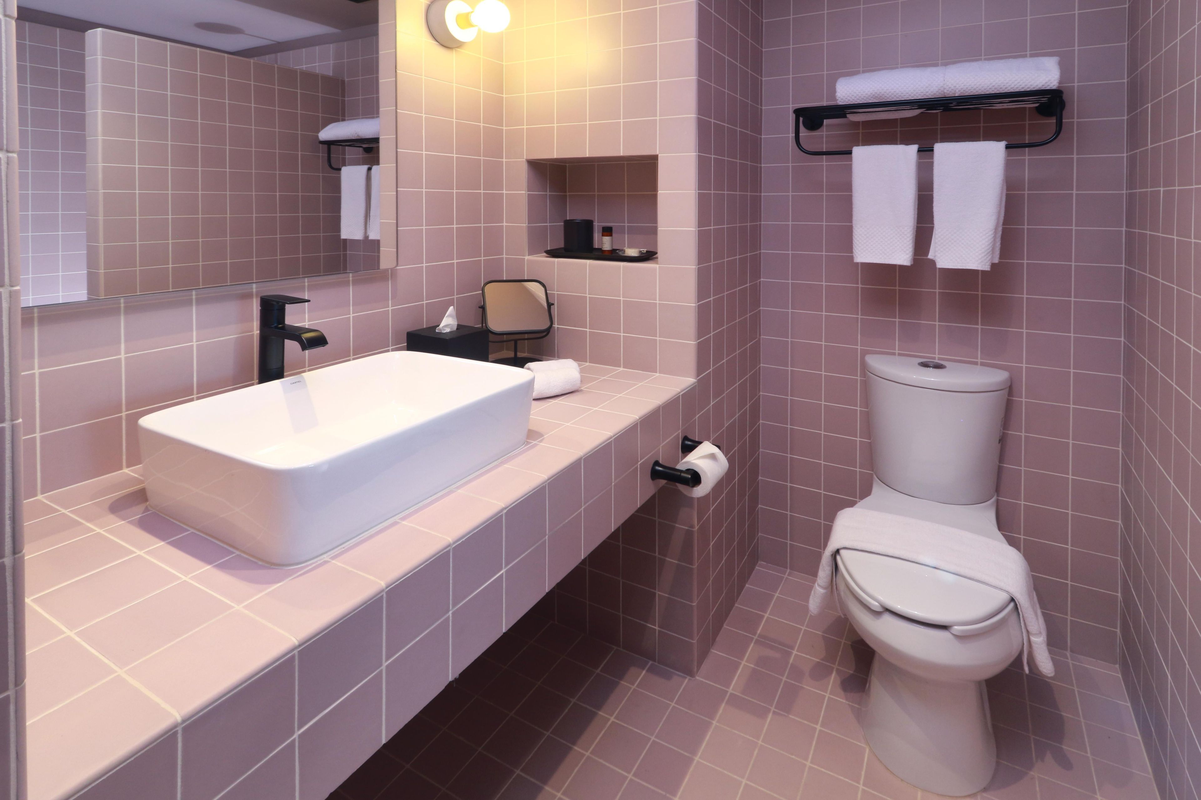 A modern bathroom with a white sink, a toilet, and a mirror.