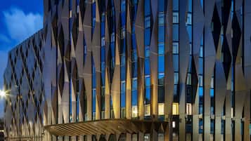 A modern building with a geometric facade and illuminated windows.