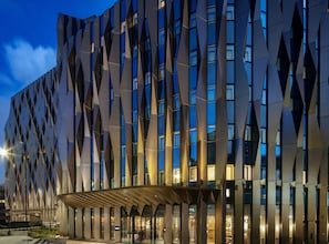 A modern building with a geometric facade and illuminated windows. - Canopy by Hilton London City (London)