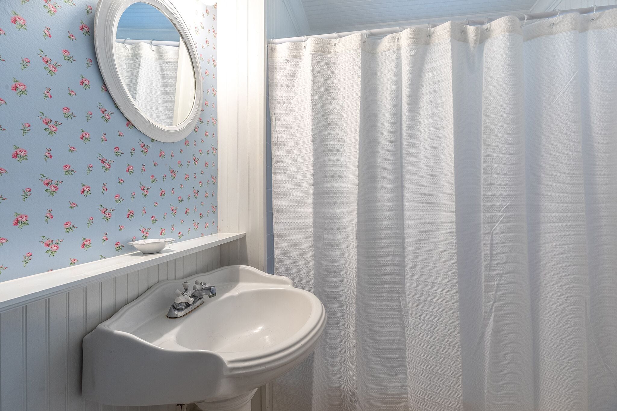 A bathroom with a white sink, a mirror, and a shower curtain.