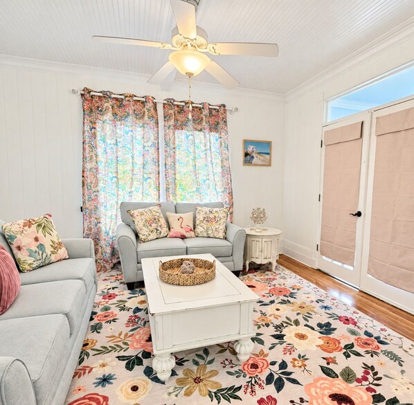 A living room with a sofa, a coffee table, and a ceiling fan.