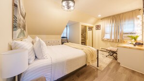 Un dormitorio con cama, mesita de noche, lámpara y espejo con iluminación.