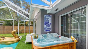 Ein Garten mit Whirlpool, einer aufblasbaren Schwanenangstalt und einem Pool mit Holzterrasse und Liegestühlen.