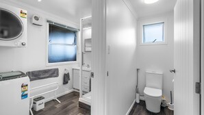 A compact bathroom with a toilet, a sink, and a window. - Nine Acres - FREE Wi-Fi (Invercargill)