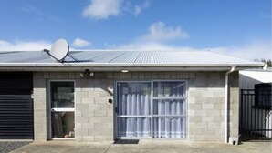 A single-story building with a satellite dish, a garage door, and a large window with curtains. - Nine Acres - FREE Wi-Fi (Invercargill)
