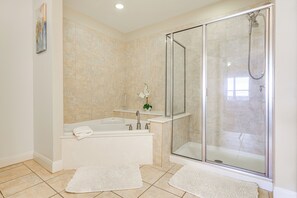 Ein modernes Badezimmer mit einer Glaskabine zur Dusche, einer freistehenden Badewanne und einem weißen Waschbecken.