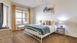 A bedroom with a bed, bedside tables, a ceiling fan, a window with curtains, and a painting on the wall. - Lake LBJ Condo w/ Private Balcony, Lake Views (Horseshoe Bay)
