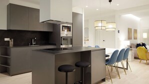 A modern kitchen with a central island, bar stools, and a dining area with chairs and a table. - Mayor Suite 8 by FeelFree Rentals (San Sebastián)