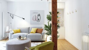 A modern living room with a grey sofa, a round ottoman, a green armchair, and a wooden column. - Salamanka by FeelFree Rentals (Donostia)