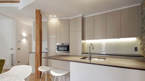 A modern kitchen with a central island, built-in oven, and a stone accent wall. - Salamanka by FeelFree Rentals (Donostia)
