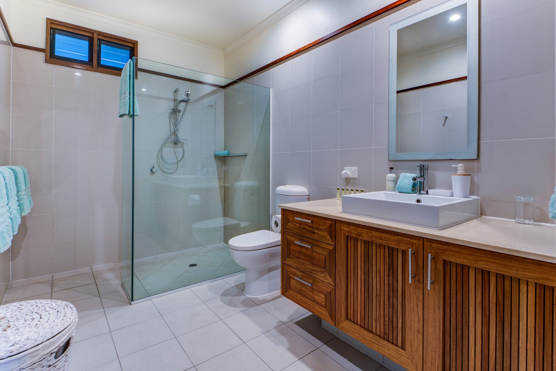 Ein modernes Badezimmer mit einer gläsernen Dusche, einer weißen Toilette und einem Holzlagerplatz mit Waschbecken.