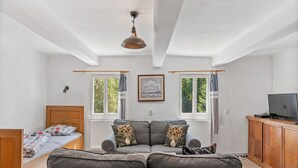 A room with a bed, a sofa, a TV, and a cabinet. - Lenora II by Interhome (Lenora)