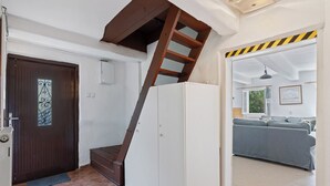A staircase leading to a second floor, a door with a decorative glass panel, and a view into a living area with a sofa and a window. - Lenora II by Interhome (Lenora)