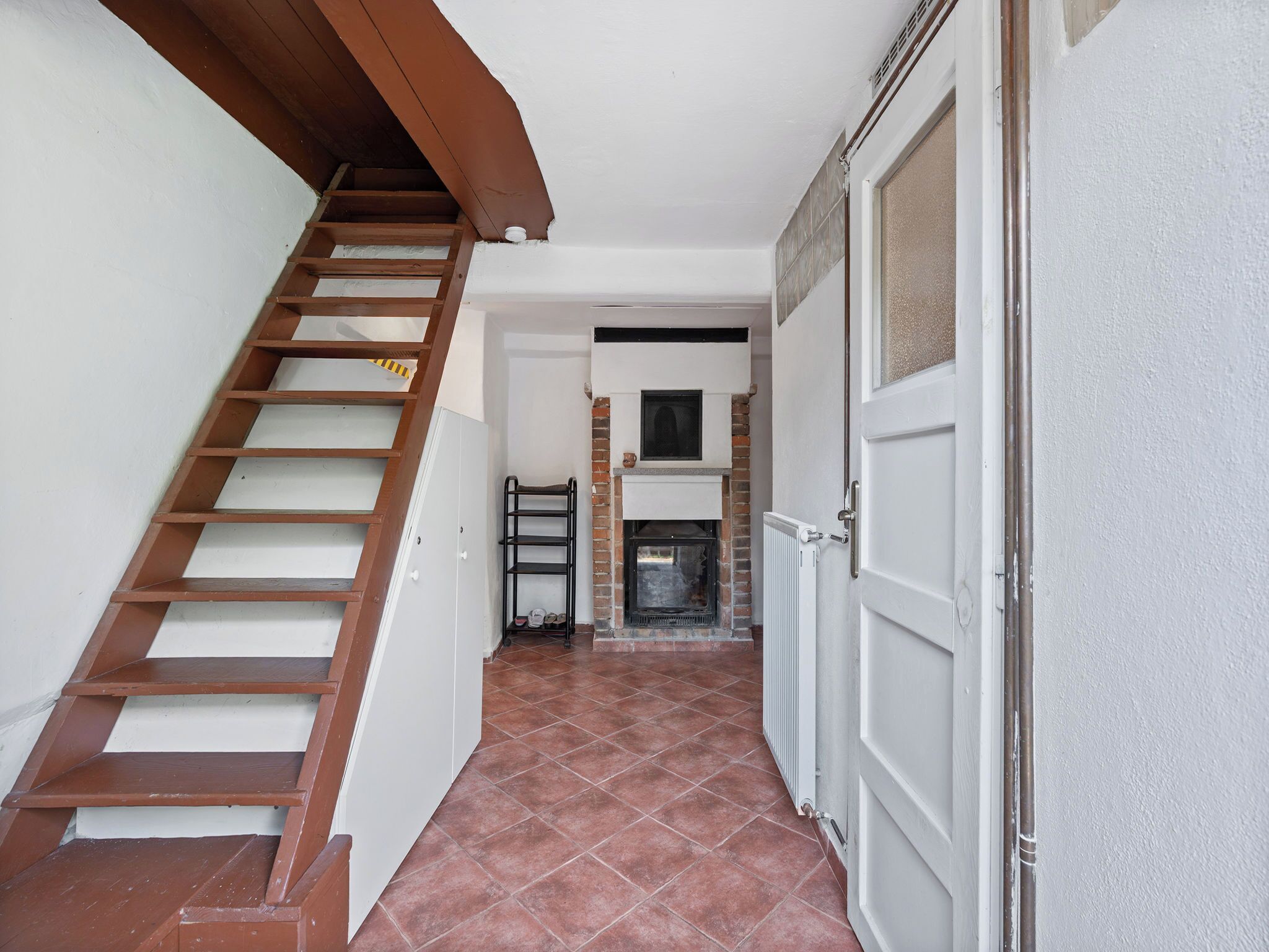 Un escalier menant à un palier où se trouvent une cheminée et une porte, sur le côté droit.
