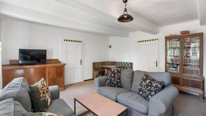 A living room with a sofa, coffee table, television, bookshelf, and a ceiling light fixture. - Lenora II by Interhome (Lenora)