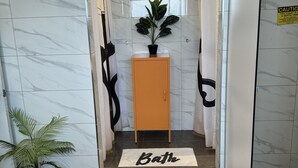 A bathroom with a marble floor, a potted plant, a cabinet, and a 'Bath' mat. - Horotiu Large Group Accommodation & Events (Horotiu)
