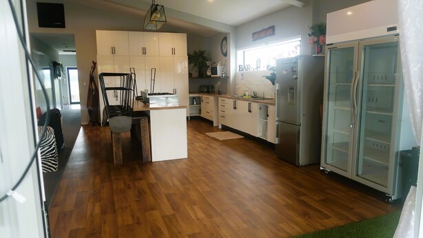A modern kitchen with wooden flooring, a central island, and a built-in refrigerator. - Horotiu Large Group Accommodation & Events (Horotiu)