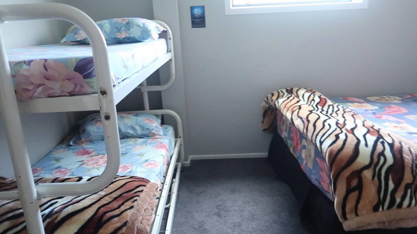 Habitación con literas, ropa de cama floral y colcha con estampado de tigre.
