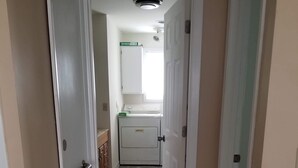 A hallway leading to a laundry room with a washing machine, a small window, and a door with a handle. - Quite and cozy / Boat ramp nearby.  (Minster)